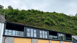 Edifici amb un pis en construcció, un garatge i una zona d'aparcament plena de cotxes.