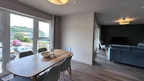 Un salon moderne avec un coin repas, de grandes fenêtres et une vue sur l’extérieur.