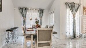 A dining area with a marble floor, a wooden table, and bar stools.