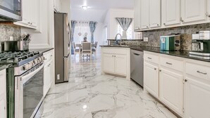 A kitchen with white cabinets, a stove, and a coffee maker.