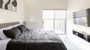 Ein Schlafzimmer mit einem Bett, einem Fernseher und einem Fenster.