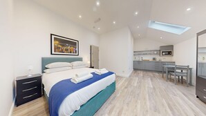 A modern hotel room with a large bed, a desk, and a kitchenette. - Bicester Court Lodge The Heritage Room | Bicester Holiday Let | 1 Beds & Sleeps 2 (Bicester)
