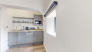 A modern kitchen with grey cabinets, a stainless steel sink, and a built-in microwave.