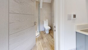 A modern bathroom with a glass shower enclosure, a toilet, and a sink area.
