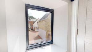 A skylight window with a view of a brick building and a paved courtyard.