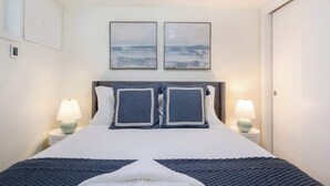A neatly arranged hotel room with a large bed, two bedside lamps, and two framed pictures on the wall. - Cozy& Chic 1BR 1BA Lower Unit Near Lake Union (Seattle)