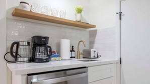 A compact kitchen with a dishwasher, a coffee maker, a toaster, and a sink. - Cozy& Chic 1BR 1BA Lower Unit Near Lake Union (Seattle)