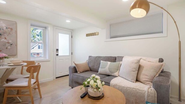 A modern living room with a grey sofa, a round coffee table, and a floor lamp. - Cozy& Chic 1BR 1BA Lower Unit Near Lake Union (Seattle)