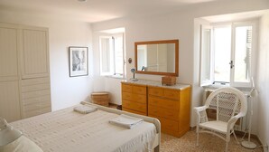 Un dormitorio con una cama, un aparador de madera, una silla y un espejo grande.