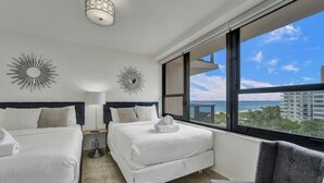 A hotel room with two beds, a large window with a view of the ocean, and decorative wall sconces. - Oceanfront Beach Retreat Beach Service 905 (Miami Beach)