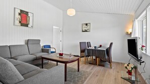 A modern living room with a grey sofa, a wooden coffee table, and a dining area with a table and chairs.