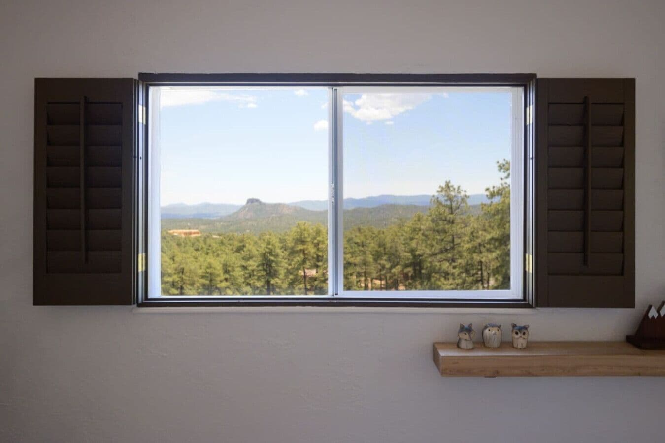 Une pièce dotée d’une grande fenêtre donnant sur une forêt et des montagnes.