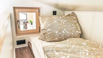 A bedroom with a bed, a window, and a small potted plant.