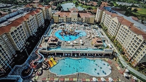 Eine Vogelperspektive eines Hotels mit mehreren Schwimmbecken, einer Wasserrutsche und einem zentralen Innenhof.