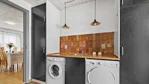 Cocina compacta con lavadora, lavamanos y salpicadero de azulejos.