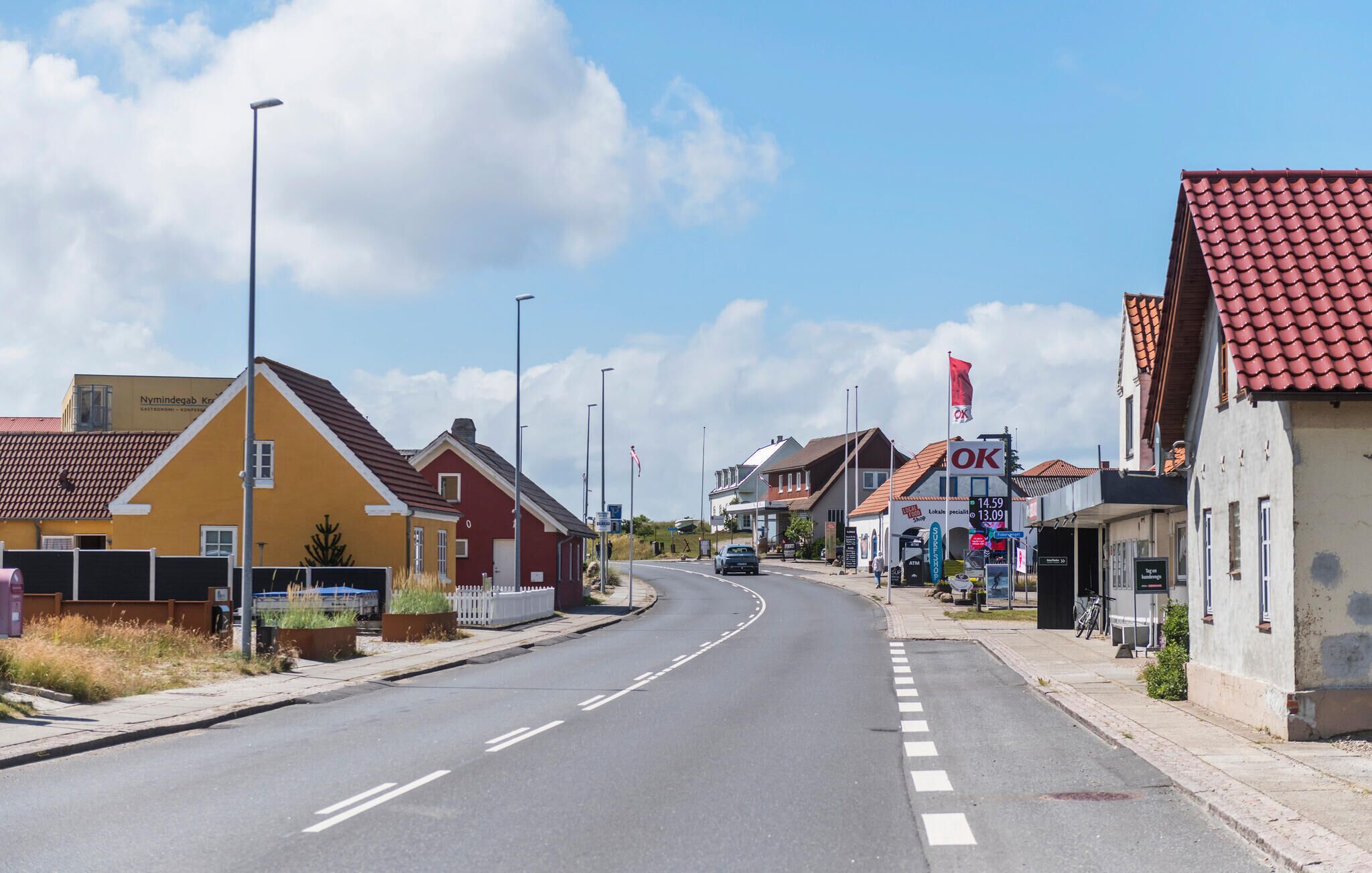 A street with houses, a road, and a sign for a shop.
