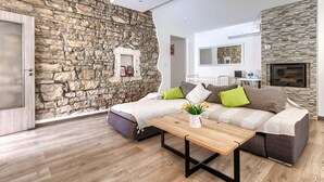 A modern living room with a stone wall, a sofa set, a coffee table, and a fireplace. - Vacation home Nina by Interhome (Barban)