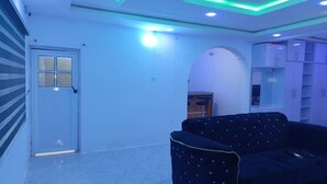 A room with a black sofa, a door, and a white wall with a window. - LUXURY ONE-BEDROOM APARTMENT IN THE HEART OF ABEOKUTA (Abeokuta)