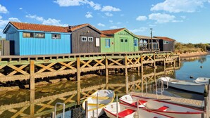 A wooden pier with colorful wooden buildings, a calm water body, and boats docked.