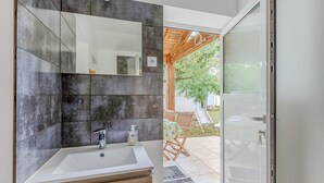 A modern bathroom with a large mirror, a white sink, and a wooden vanity.