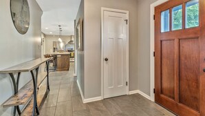 A hallway with a wooden door, a white door, and a mirror on the wall.