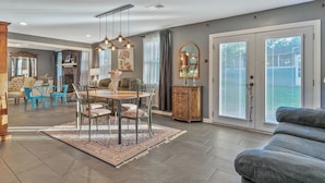 A spacious living area with a dining table, blue chairs, a gray sofa, and a wooden cabinet.