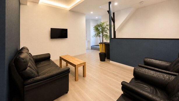 Een moderne woonkamer met leren banken, een houten salontafel, een flatscreen televisie en een kamerplant.