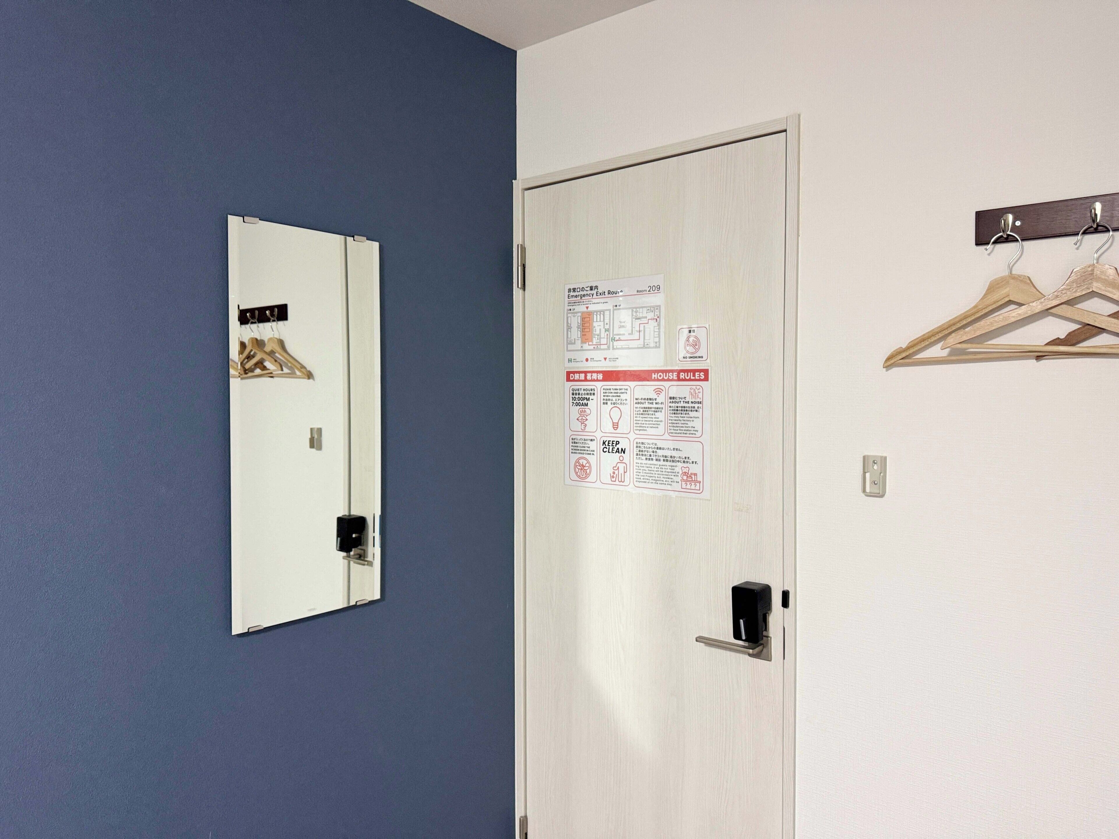 A door with a mirror and a notice board, a coat rack, and a light switch.