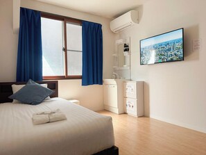 Ein Hotelzimmer mit Bett, Schreibtisch, Spiegel, Klimaanlage und Stadtblick an der Wand.