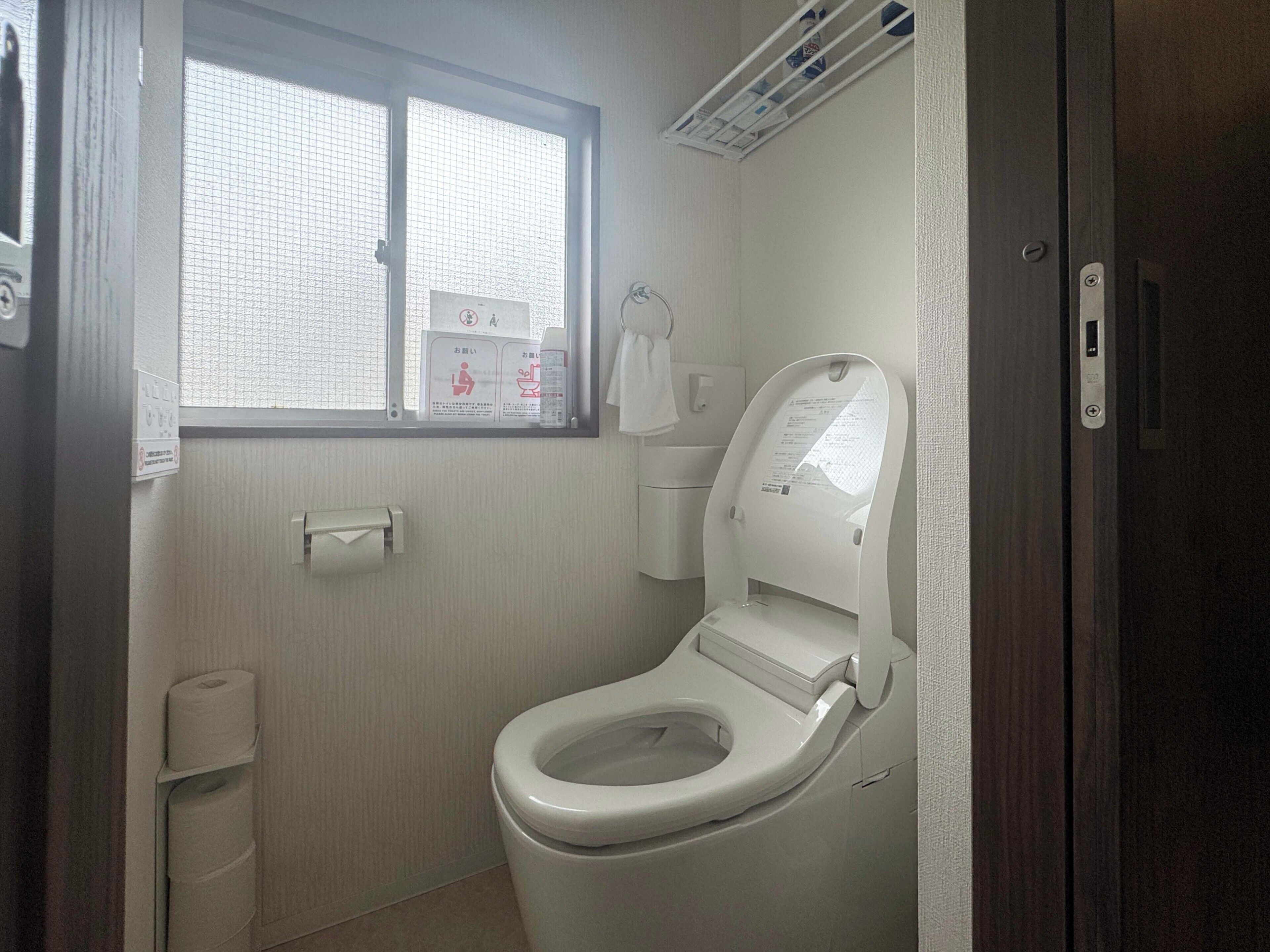 A small, clean bathroom with a toilet, a window, and a towel rack.
