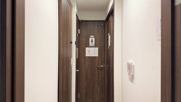 A narrow hallway with wooden doors, a ceiling light, and a sign indicating a women's restroom.