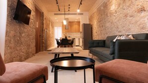 Una sala moderna con una pared de piedra, un televisor de pantalla plana, un sofá, una mesa de centro y un comedor con sillas y una mesa.