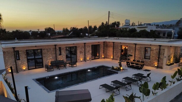 Un área de piscina en la azotea, con una piscina rectangular, sillas de descanso y mesas.
