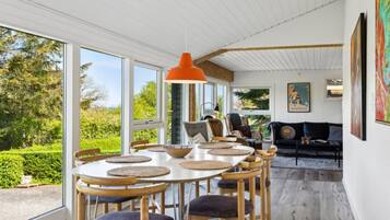Un coin repas avec une table ronde, des chaises en bois et une suspension orange.