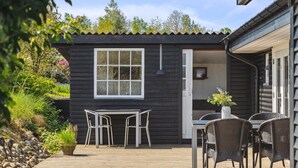 A wooden deck with a table and chairs, a small window, and a door leading to a covered area. - "Sölvy" - 300m from the sea by Interhome (Børkop)