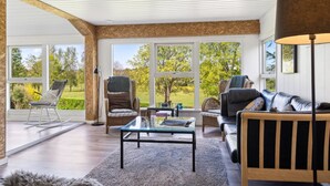A spacious living room with a glass coffee table, a sofa, and two rocking chairs. Large windows offer a view of the outdoors. - "Sölvy" - 300m from the sea by Interhome (Børkop)