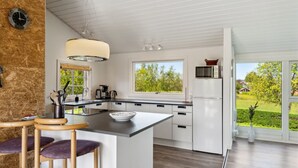 A modern kitchen with a central island, white cabinetry, and a view of the outdoors. - "Sölvy" - 300m from the sea by Interhome (Børkop)