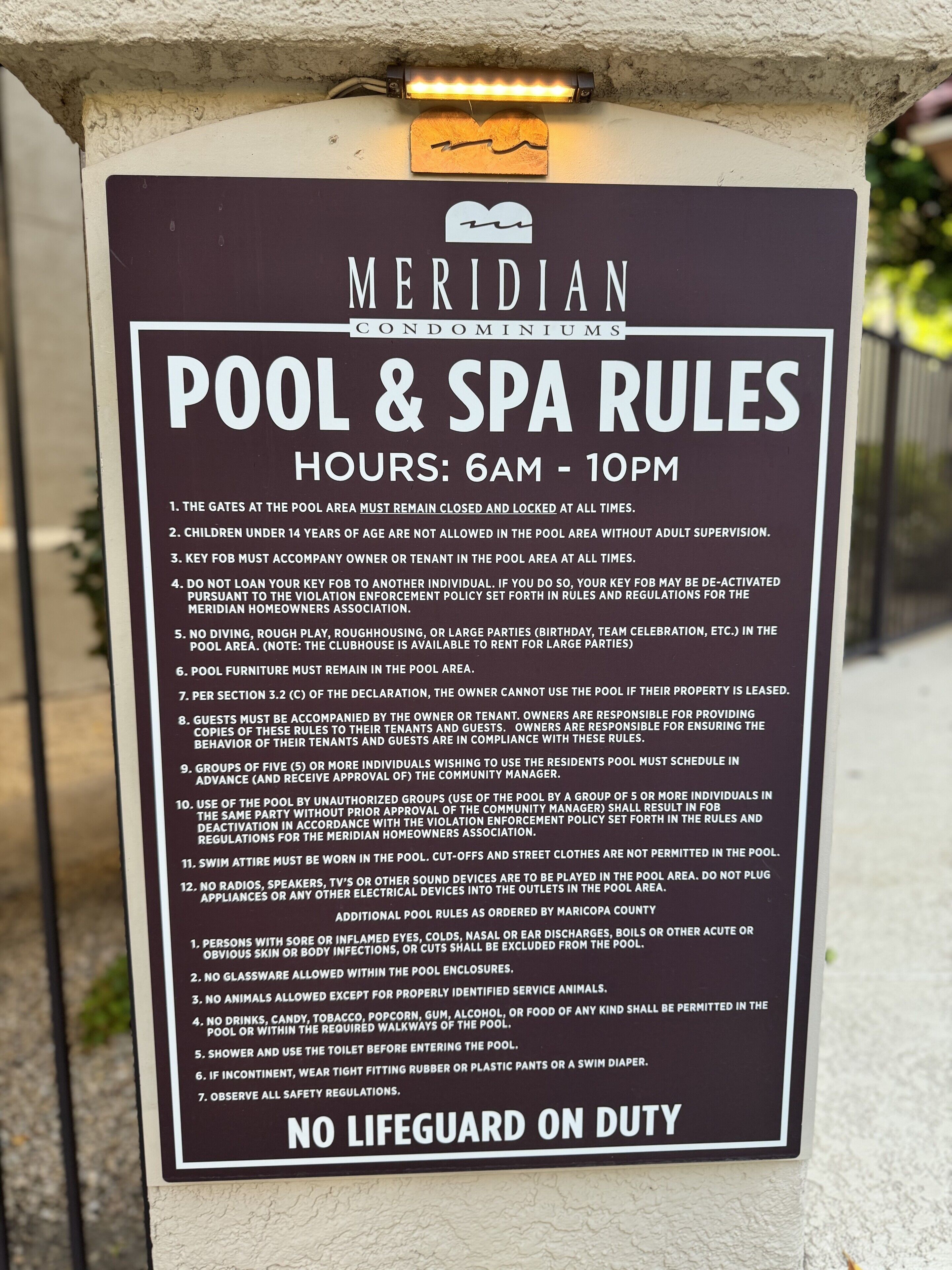 A pool and spa rules sign for Meridian Condominiums, listing operating hours and various rules.