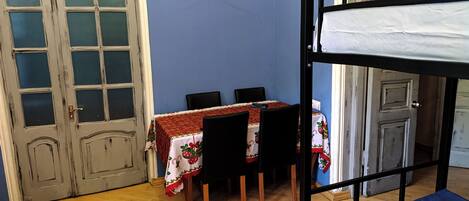 A room with a bunk bed, a table with chairs, and a door with frosted glass panels.