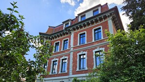 Ein mehrgeschossiges Gebäude mit roter Backsteinfassade, weißem Zierrat und zahlreichen Fenstern.