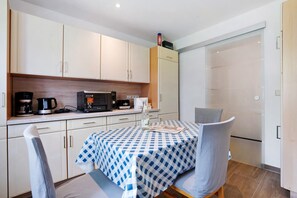 Cozinha compacta com micro-ondas, cafeteira e uma mesa com toalha de mesa xadrez.