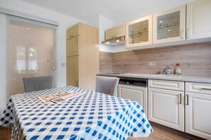 A kitchen with a checkered tablecloth, a dishwasher, and light-colored cabinets. - Holiday Apartment 'Gästewohnung Am Schwanenteich' with Wi-Fi (Mittweida)