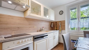 A kitchen with white cabinets, a dishwasher, and a window with a view of greenery.