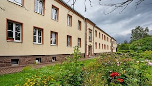 A building with multiple windows and a brick pathway leading to the entrance.