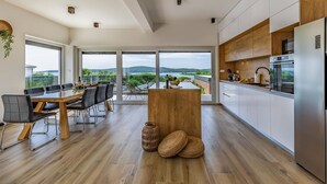 Een moderne keuken met een groot schiereiland, houten kastjes en uitzicht op de omgeving.