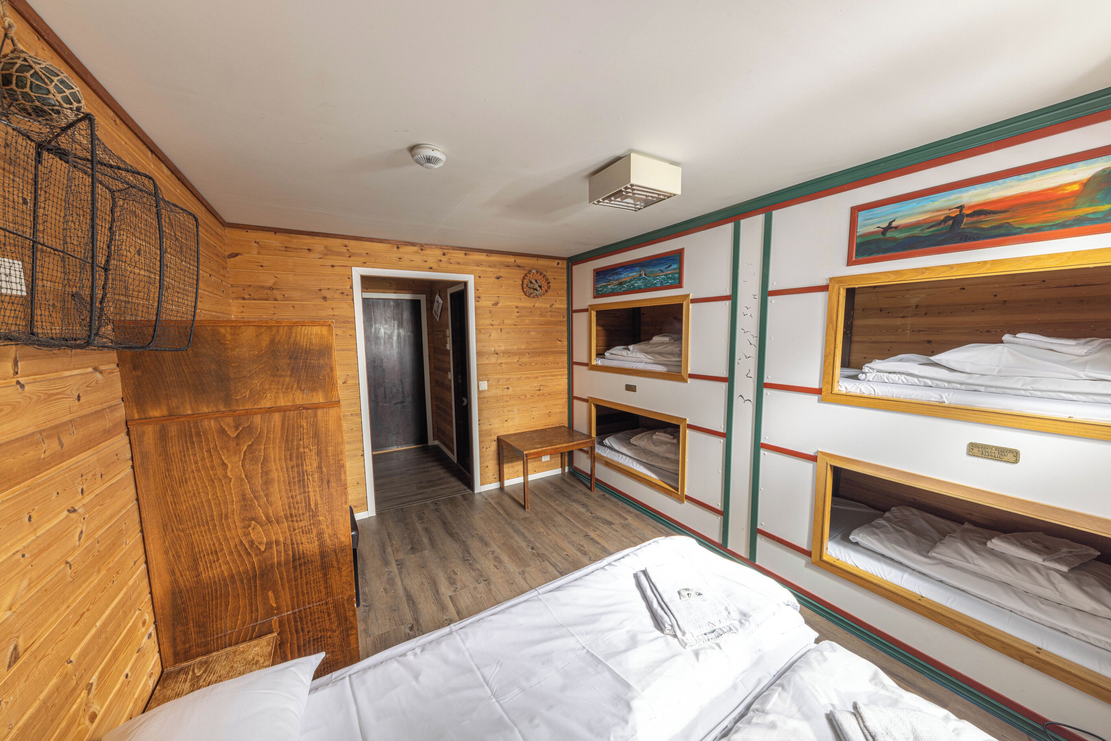 A wooden-paneled room with bunk beds, a bench, and a painting on the wall.