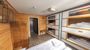 A wooden-paneled room with bunk beds, a bench, and a painting on the wall.