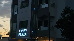 Un edificio moderno con un letrero que dice "GRANDI PLAZA" y otro letrero con texto en árabe.