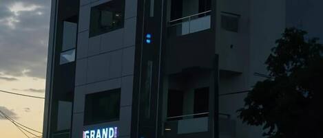 A modern building with a sign that reads "GRANDI PLAZA" and another sign with Arabic text.