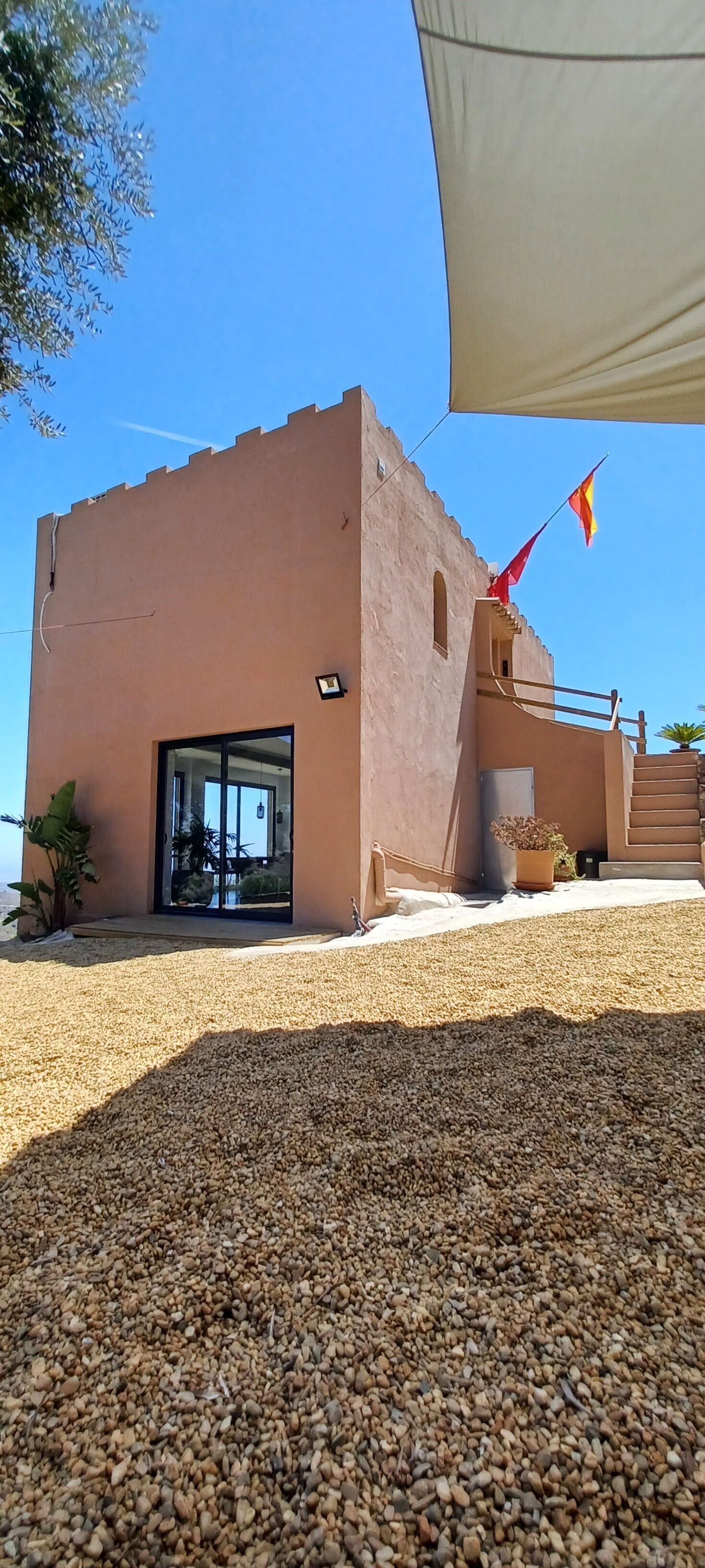 A modern building with a beige facade, a glass entrance, and a red flag.